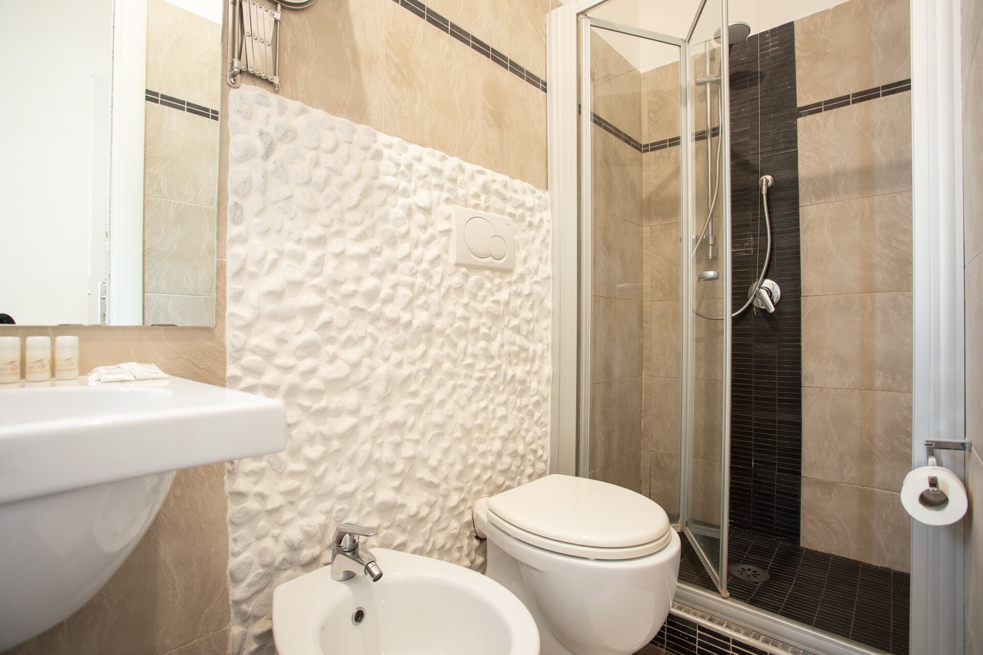 Un baño con lavamanos blanco, inodoro y zona de ducha con mampara de vidrio.