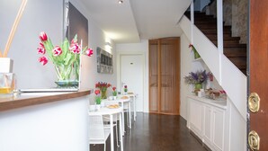 A hallway with a dining area, a staircase, and a wooden door. - Romanticasa Navona  (Rome)