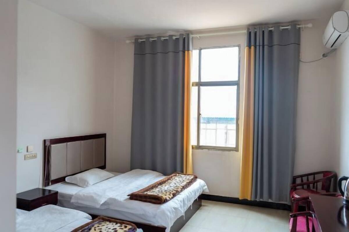 A hotel room with a bed, a desk, a chair, and a window with curtains.