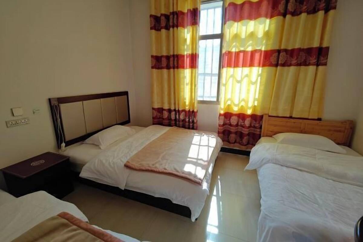 A hotel room with two beds, a nightstand, and a window with curtains.