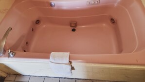 A bathtub with a faucet, a drain, and a control panel. - Budget inn (Texarkana)