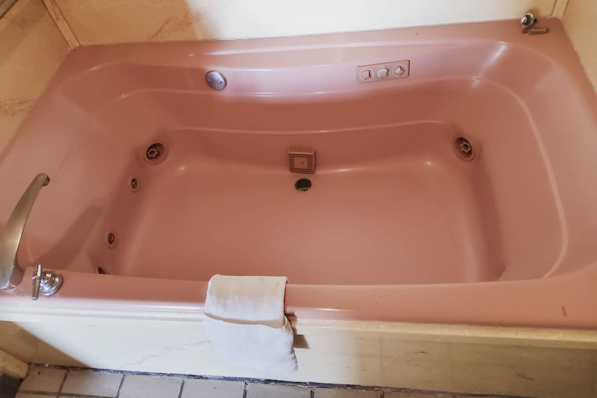 A bathtub with a faucet, a drain, and a control panel.