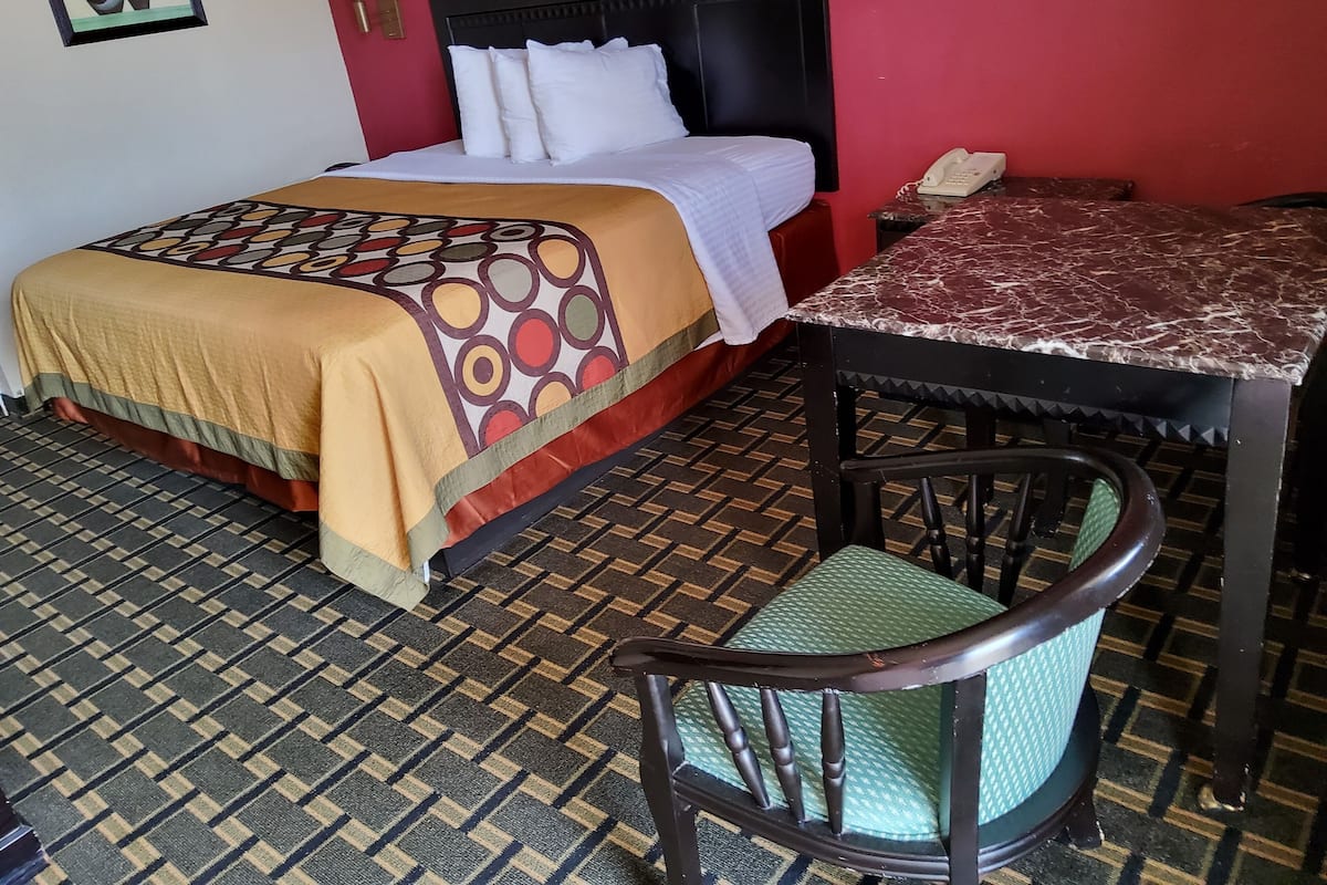 A hotel room with a bed, a table, a chair, and a telephone.