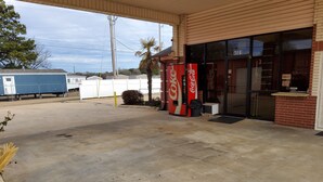 A gas station with a Coca-Cola vending machine, a parking lot, and a building with a 'VACANCY' sign. - Budget inn (Texarkana)