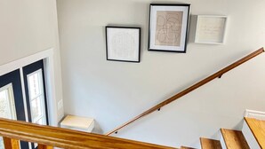 A staircase with wooden handrails and a light-colored wall with three framed artworks. - Upper Unit 1067 Rawding  (Port Williams)