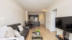 Ein modernes Wohnzimmer mit Ledersofa, Glastisch und Fernseher auf einem Lowboard.