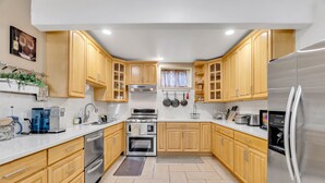 Una cocina moderna con gabinetes de madera, electrodomésticos de acero inoxidable y suelo de baldosas.