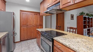 A kitchen with wooden cabinets, a stainless steel refrigerator, a built-in oven, and a granite countertop. - Spacious Private Vacation Home 3BR/2Bth - Family-sized, Big Backyard (Tallahassee)