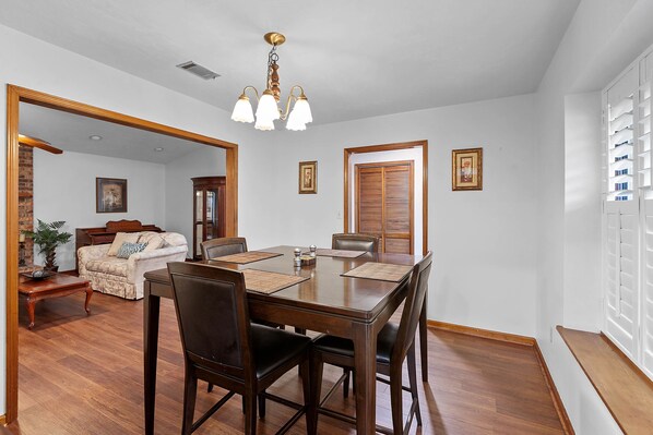 A dining room with a wooden table and chairs, a chandelier, and a brick wall. - Spacious Private Vacation Home 3BR/2Bth - Family-sized, Big Backyard (Tallahassee)