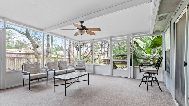 A sunroom with large windows, a ceiling fan, and a seating area with a coffee table. - Spacious Private Vacation Home 3BR/2Bth - Family-sized, Big Backyard (Tallahassee)