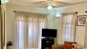 Een woonkamer met een bank, fauteuils, een televisie en gordijnen.