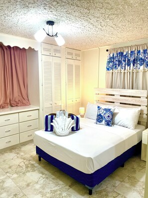 Un dormitorio con cama, mesita de noche, cómoda, armario y ventilador de techo.