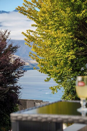 A view of a body of water with mountains in the distance, a glass of wine, and a wooden structure. - Sarahs Scenic Stay | Mountain Lake Views (Queenstown)