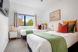 A hotel room with two beds, a large window, a painting on the wall, and a side table with a lamp. - Sarahs Scenic Stay | Mountain Lake Views (Queenstown)