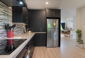 A modern kitchen with dark cabinetry, a stainless steel refrigerator, and a built-in stove. - Sarahs Scenic Stay | Mountain Lake Views (Queenstown)