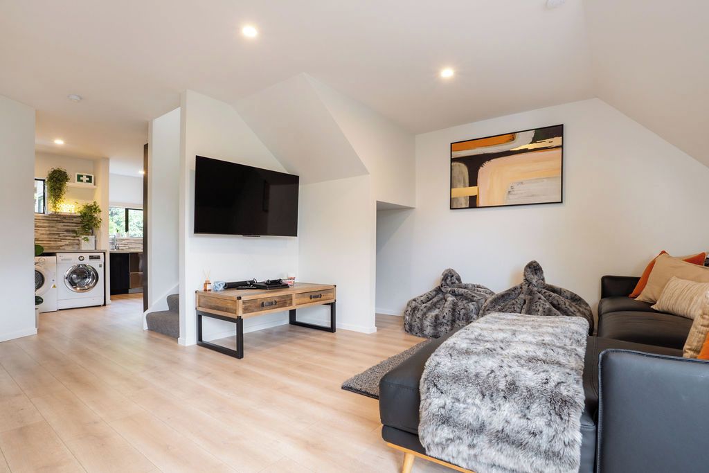 A modern living room with a flat-screen TV, a wooden coffee table, a sofa, and a large painting on the wall.