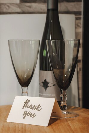 Two wine glasses on a wooden surface with a 'thank you' card in front. - Sarahs Scenic Stay | Mountain Lake Views (Queenstown)