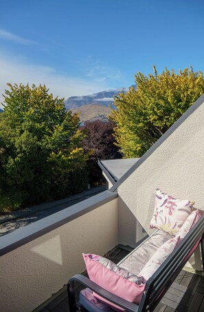 Ein Balkon mit Stuhl und Kissen mit Blick auf eine Berglandschaft.