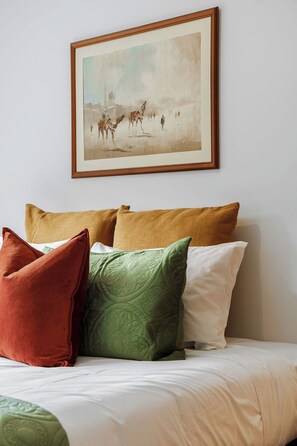 Un lit avec plusieurs oreillers et un tableau encadré accroché au mur au-dessus.