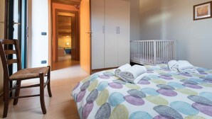 Een slaapkamer met een bed, een stoel, een ledikant en een kledingkast.