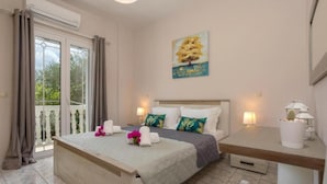 A bedroom with a bed, a desk, a chair, a painting, and a window with curtains. - Antigoni s Family House - Antigoni s Family House (Zakynthos)