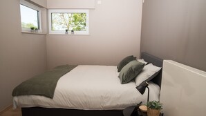 A bedroom with a bed, a bedside table with a plant, and a window with plants on the sill. - Casa Tibella is an attractively furnished holiday home. (Ichtegem)