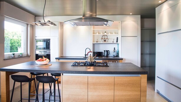 A modern kitchen with a central island, bar stools, a kettle, and built-in appliances. - Casa Tibella is an attractively furnished holiday home. (Ichtegem)