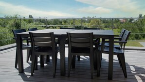 A deck with a table and chairs, overlooking a green landscape. - Casa Tibella is an attractively furnished holiday home. (Ichtegem)