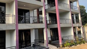 A multi-story residential building with balconies, a brick-paved ground, and a clear sky. - NL JOSEPHINES APARTMENTS (Kampala)