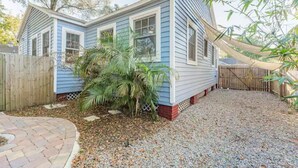 A small house with a blue exterior, a wooden fence, and a gravel driveway.