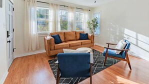A living room with a brown leather sofa, a blue armchair, a wooden coffee table, and a ceiling fan.