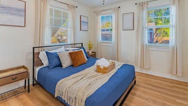 A bedroom with a bed, a ceiling fan, and windows with curtains.