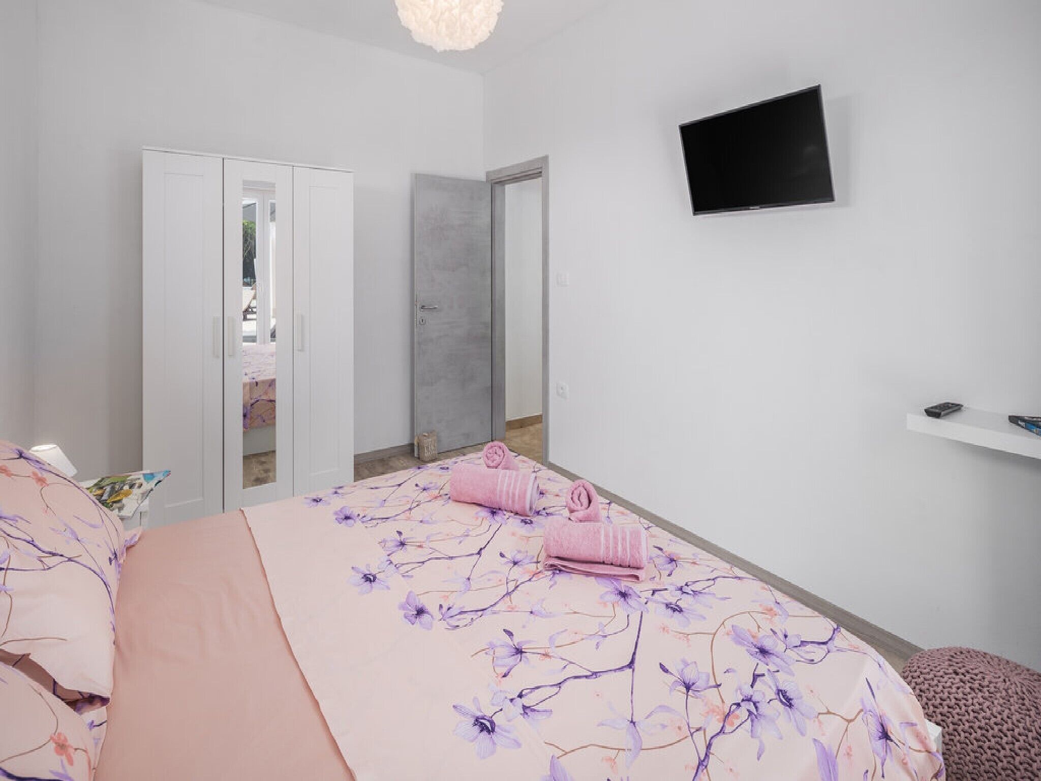 Een slaapkamer met een bed, een televisie, een kledingkast en een spiegel.
