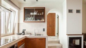 Una cocina con armarios de madera, horno empotrado, un lavamanos y una ventana.