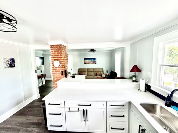 A modern kitchen with white cabinetry, a brick accent wall, and a large island.