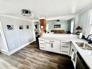 A modern kitchen with white cabinetry, a central island, and a brick accent wall.