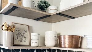 A kitchen with black and white star-patterned tiles, white storage shelves, and various kitchen utensils and cookware. - High Point Corner - Best Location! (Memphis)