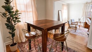 A dining area with a wooden table and four chairs, a potted plant, and a chandelier. - High Point Corner - Best Location! (Memphis)
