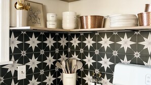 A kitchen with black and white star-patterned tiles, white and copper cookware, and a gas stove. - High Point Corner - Best Location! (Memphis)