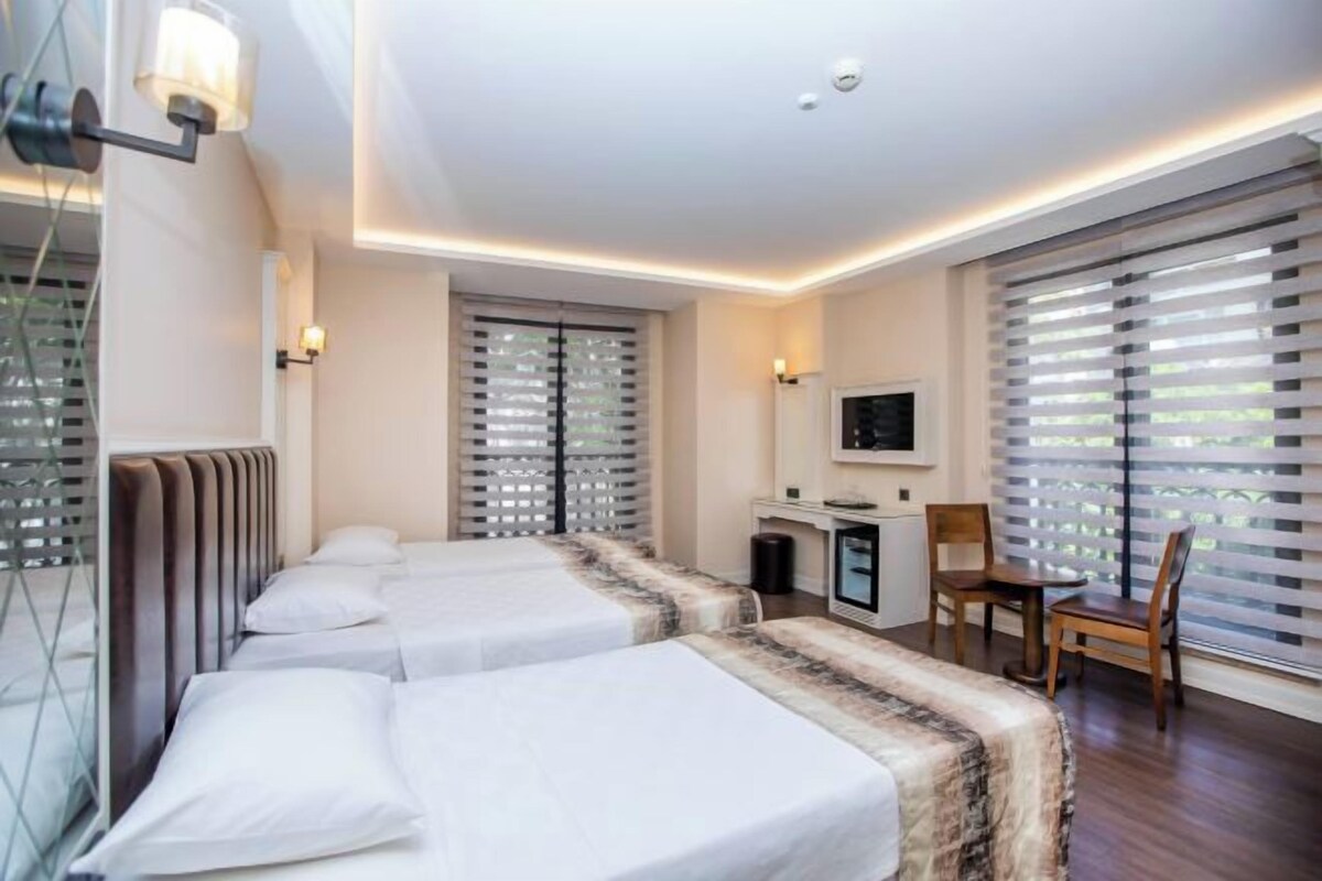A hotel room with two beds, a desk, and a TV.