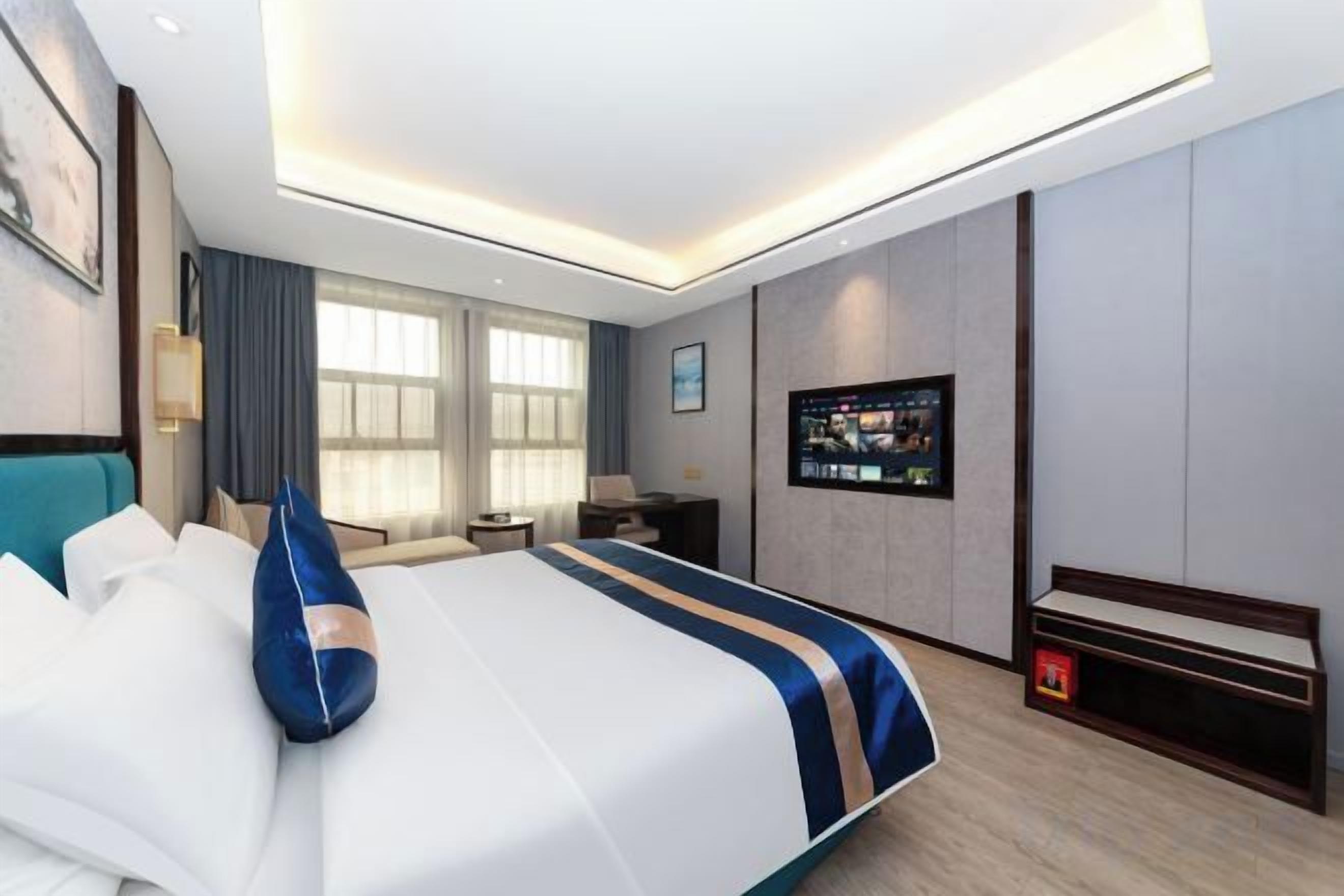 Una habitación de hotel moderna con una cama grande, un escritorio, un televisor y un banco.