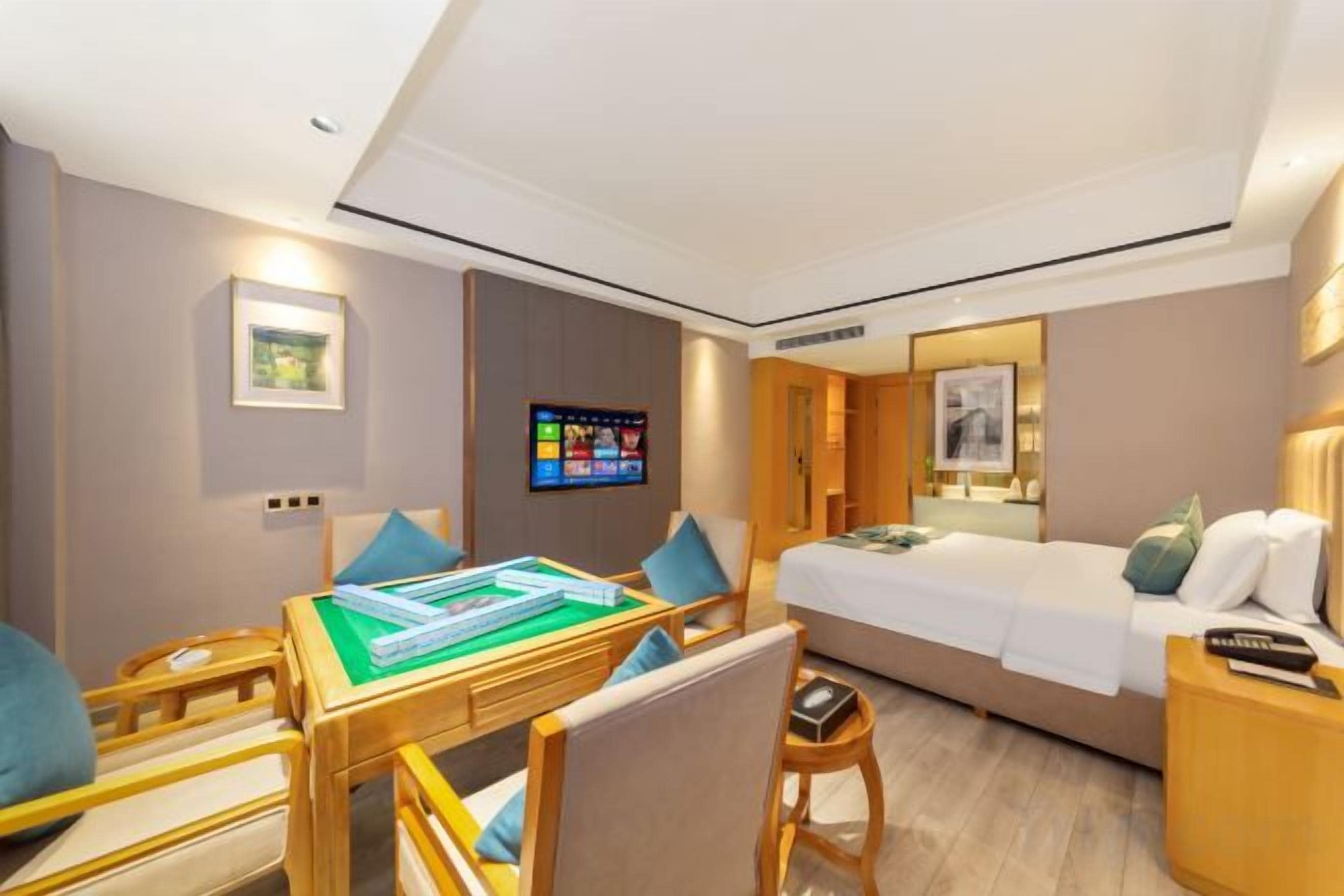 Habitación de hotel con cama, escritorio con silla, televisor y una mesita.