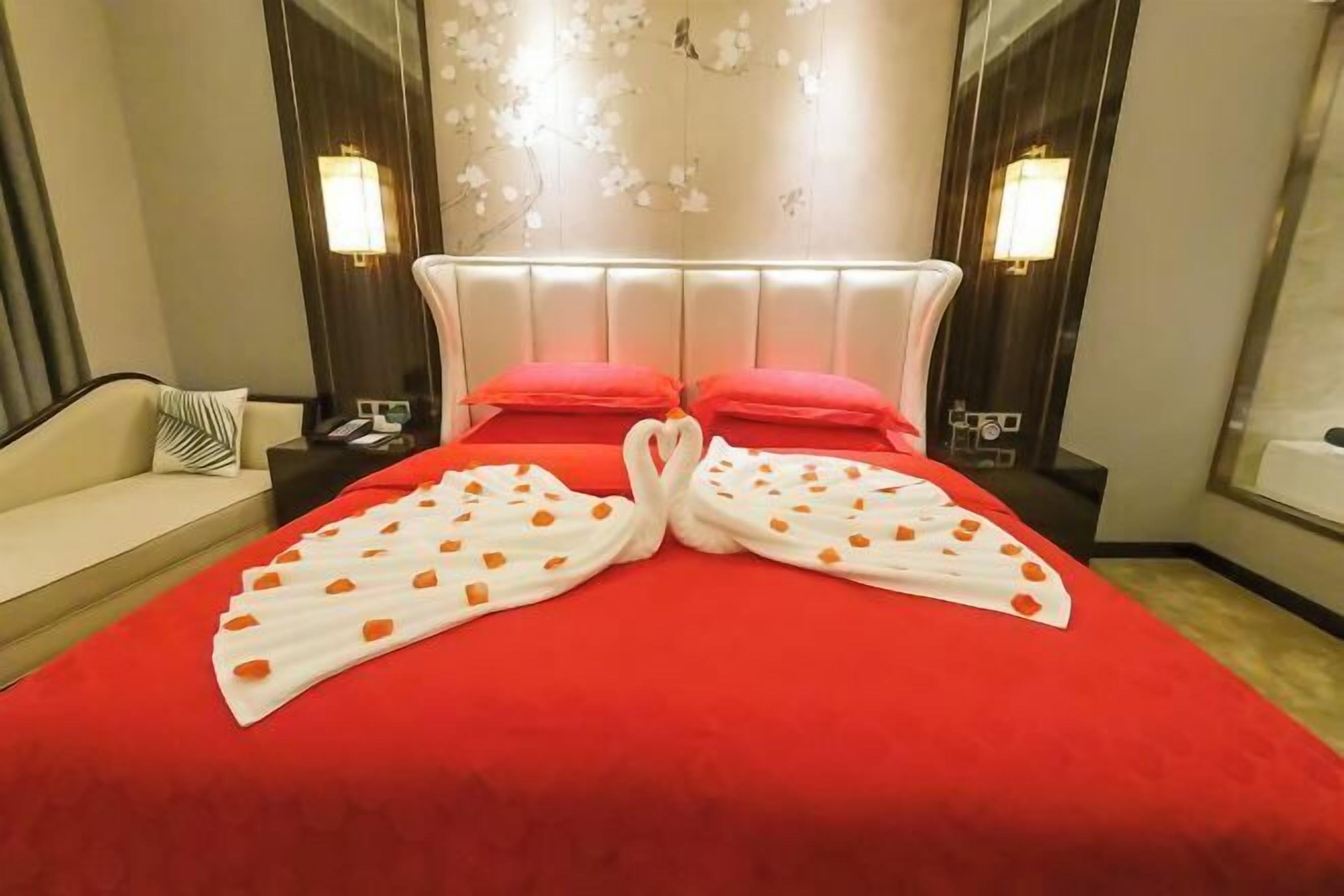 Ein Hotelzimmer mit rotem Überwurf, einem weißen Kopfteil und zwei roten Kissen.