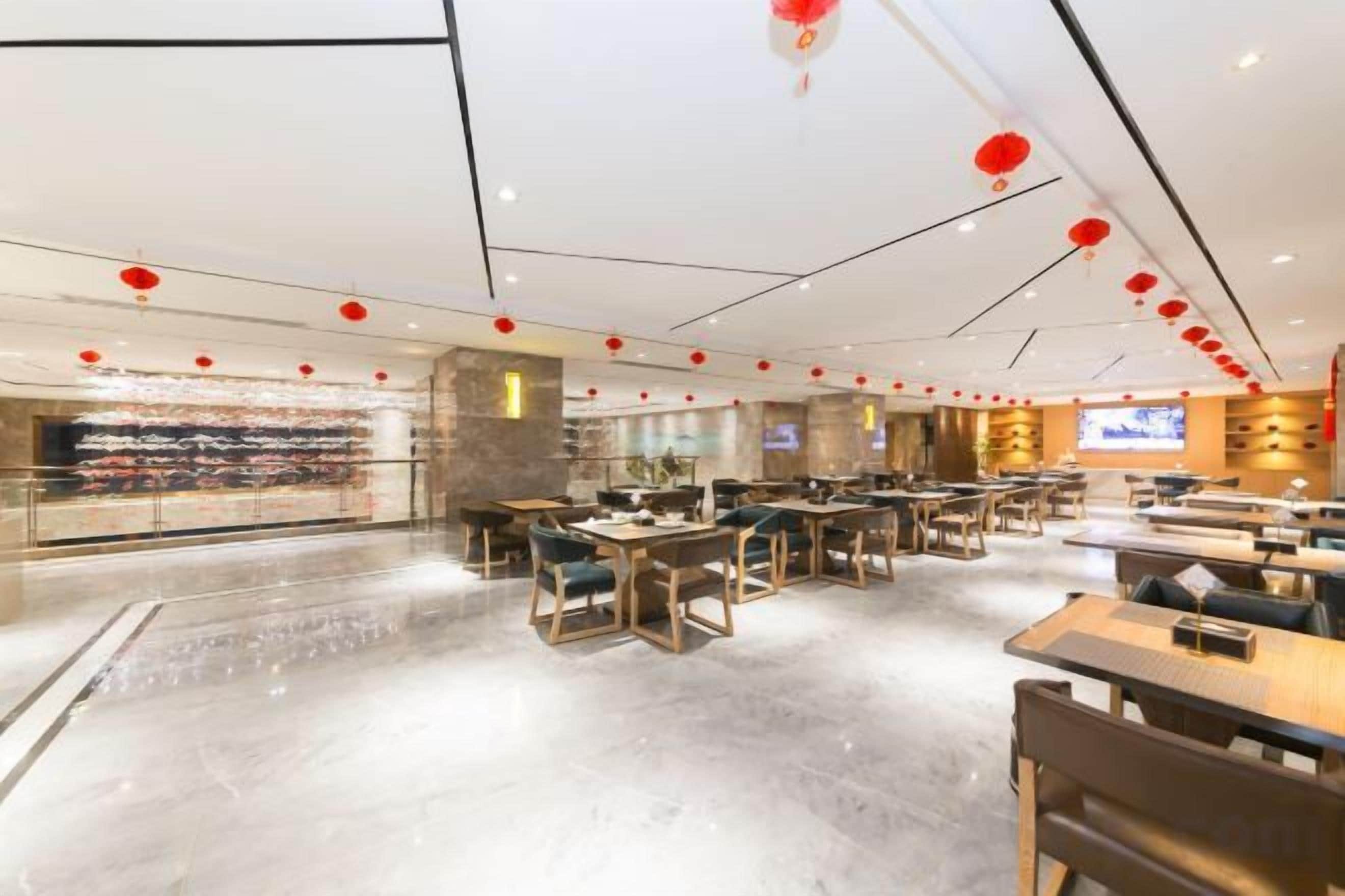 A spacious restaurant with multiple dining areas, a visible counter with food items, and a television screen.