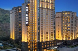 Un hotel moderno de gran altura con varios pisos, ventanas amplias y una entrada destacada.