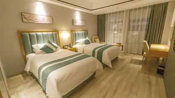A hotel room with two beds, a desk, and a chair.
