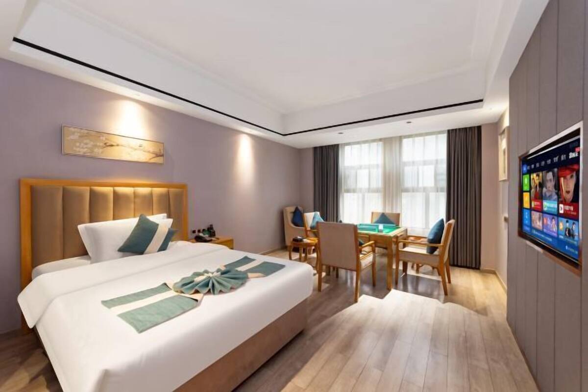 Una habitació d'hotel amb un llit gran, una taula de treball i una televisió.