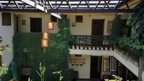 Un atrio de varios niveles con techo de vidrio, follaje verde y decoración tradicional.