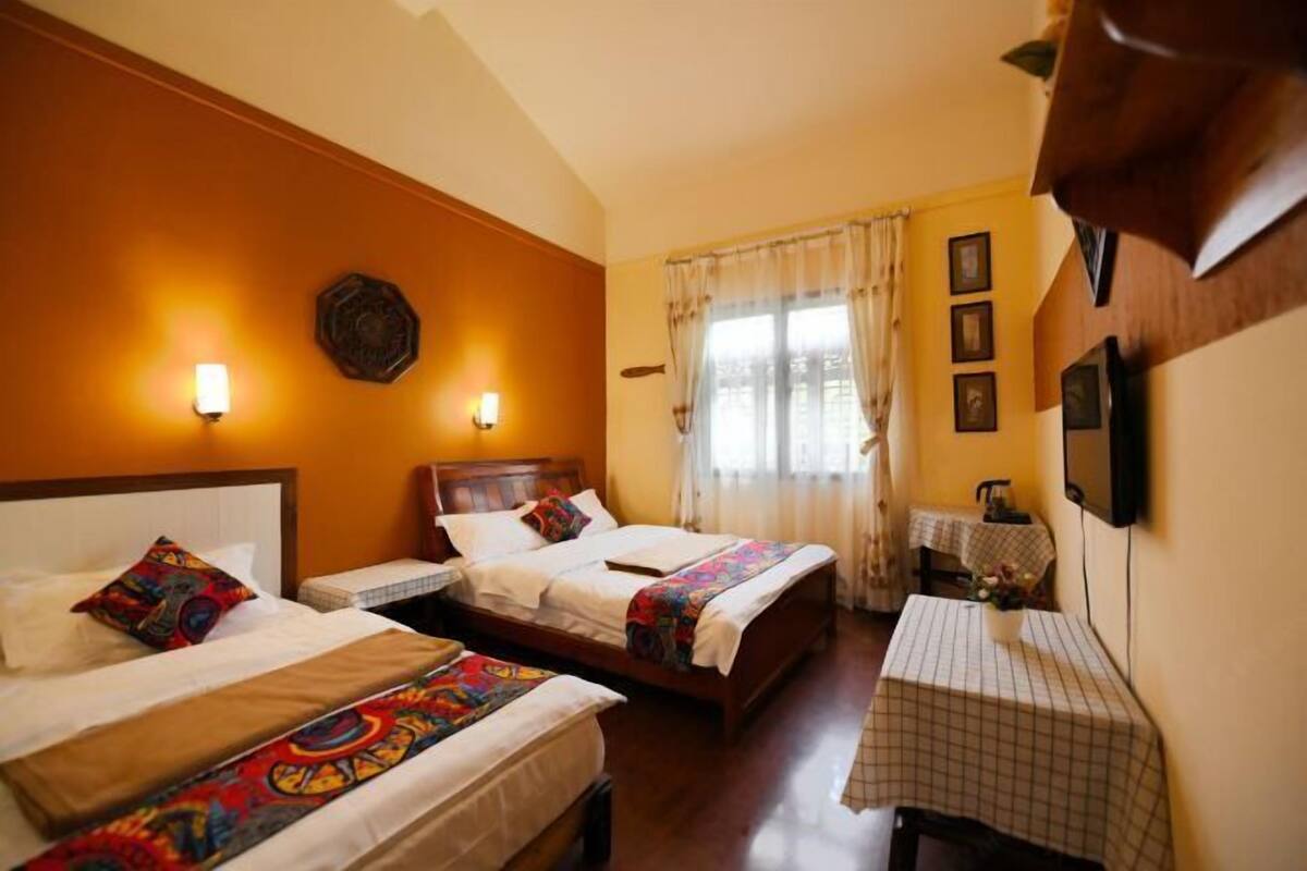 A hotel room with two beds, a small table, and a TV.