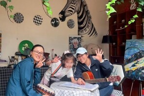 A room with a round table, a guitar, and a painting on the wall.